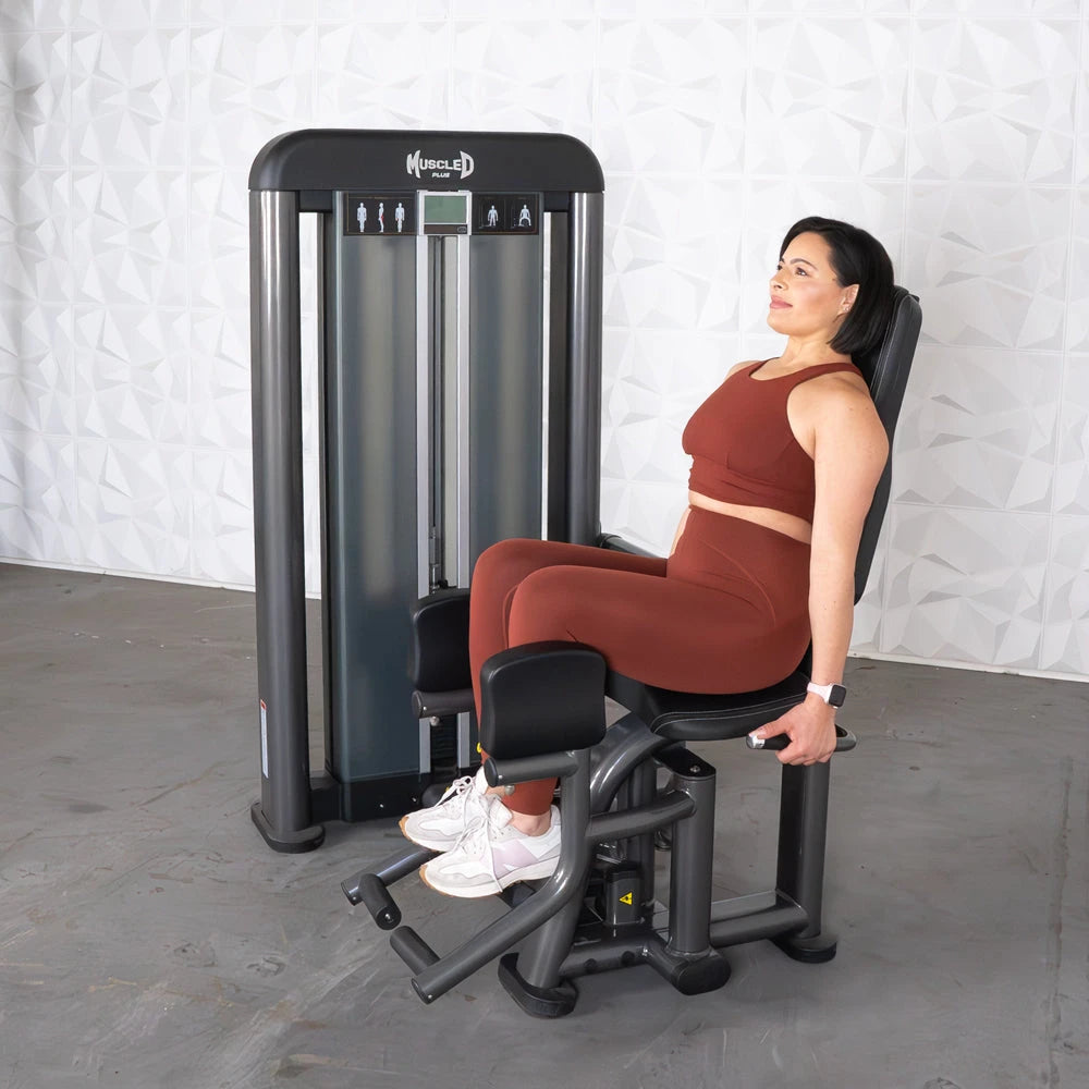 Woman sits on Muscle D Elite Plus Outer Thigh machine exercising.
