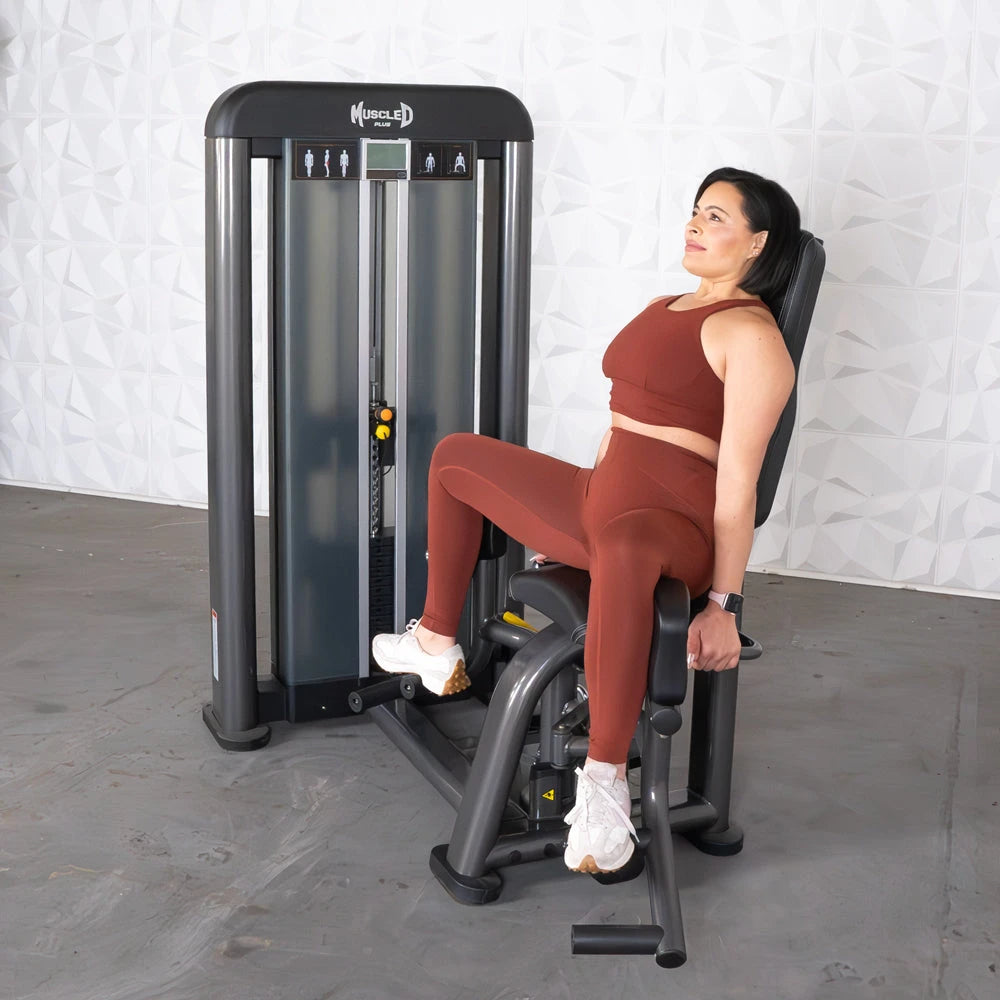 Woman using Muscle D Fitness Elite Plus outer thigh machine in gym.