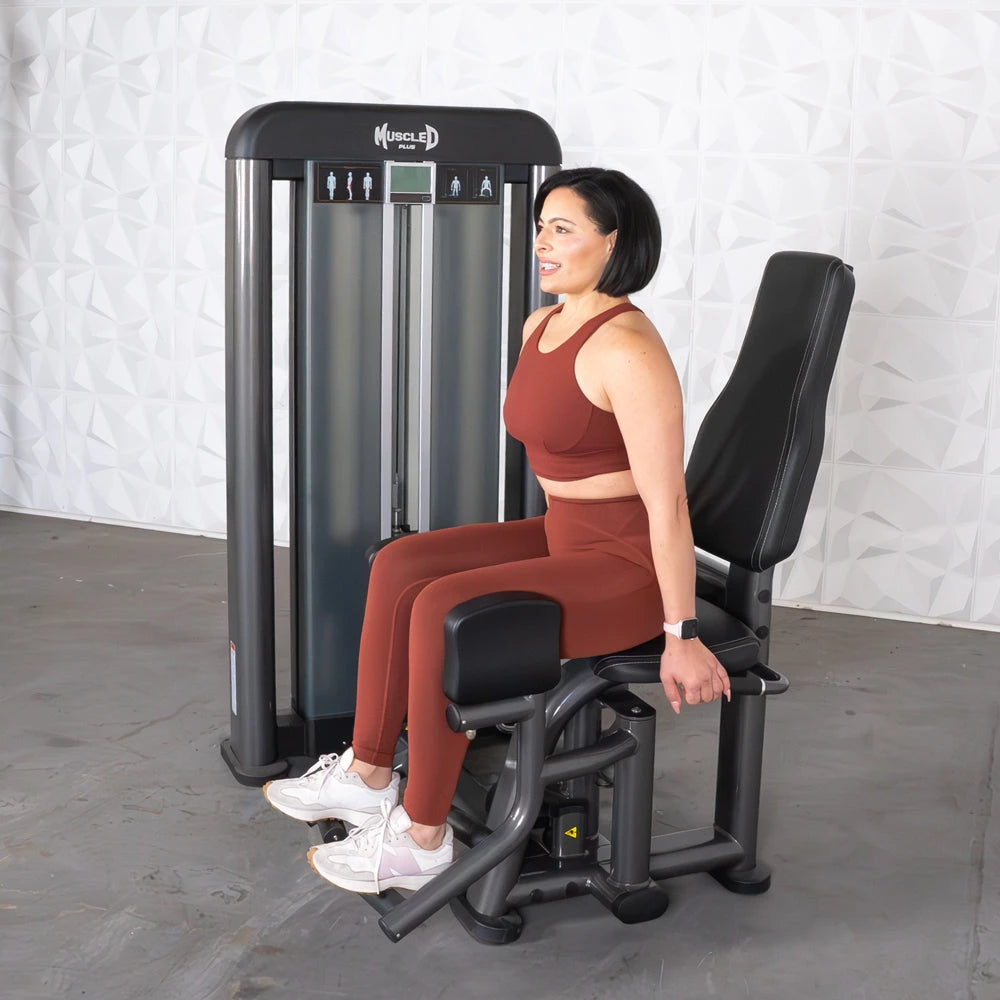 Woman using Muscle D Elite Plus outer thigh machine in gym.