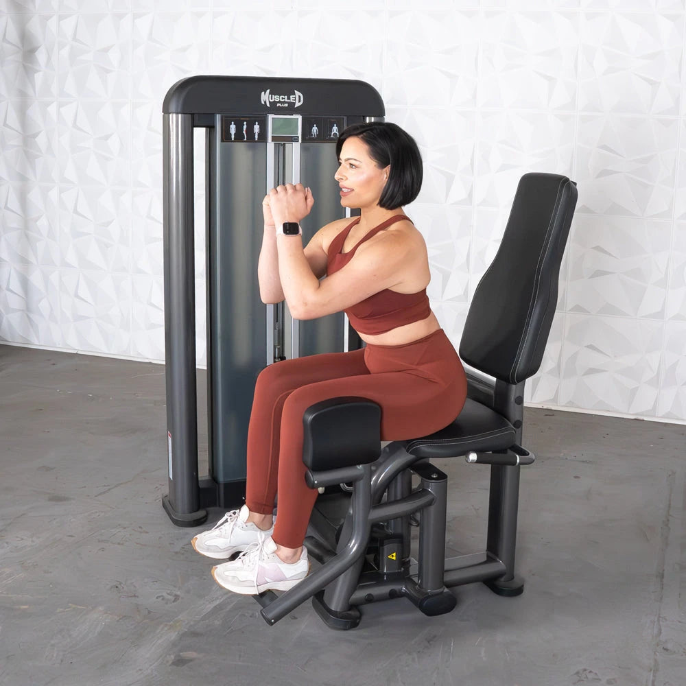 Woman using a seated outer thigh/adductor gym machine.