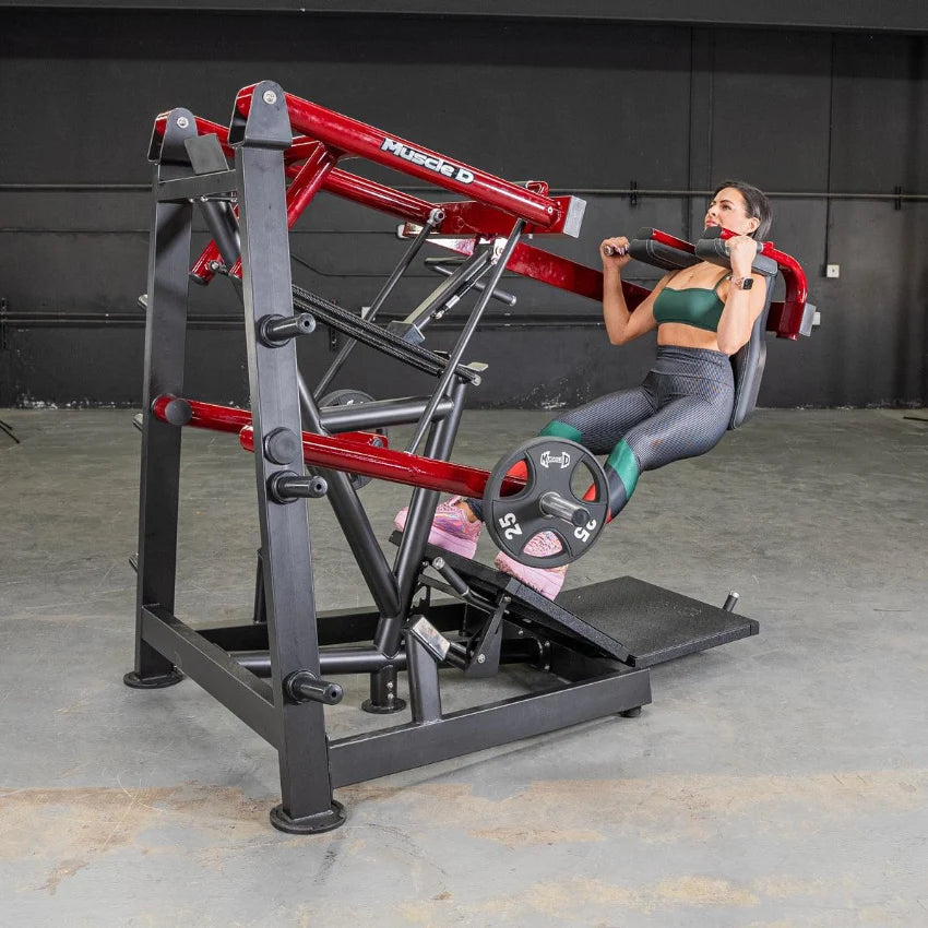 Woman using a red and black Muscle D Power Leverage Pendulum Squat machine in gym.