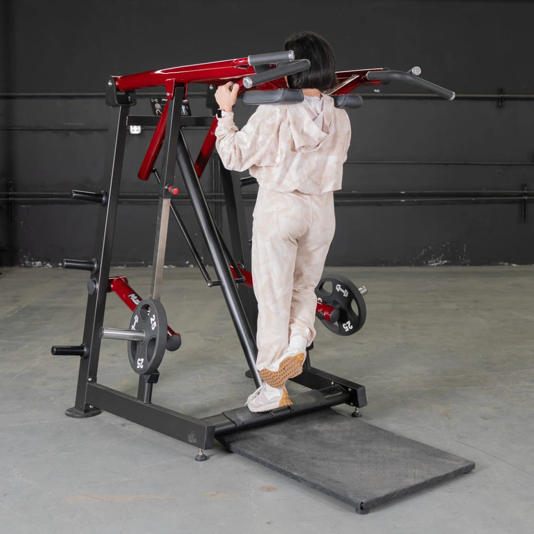 Person in a white tracksuit using a power-leverage calf/press machine in a gym.