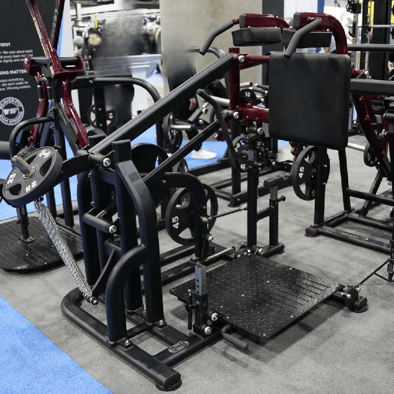 Pro Strength drop-squat machine in gym with 45 lb weight plates.