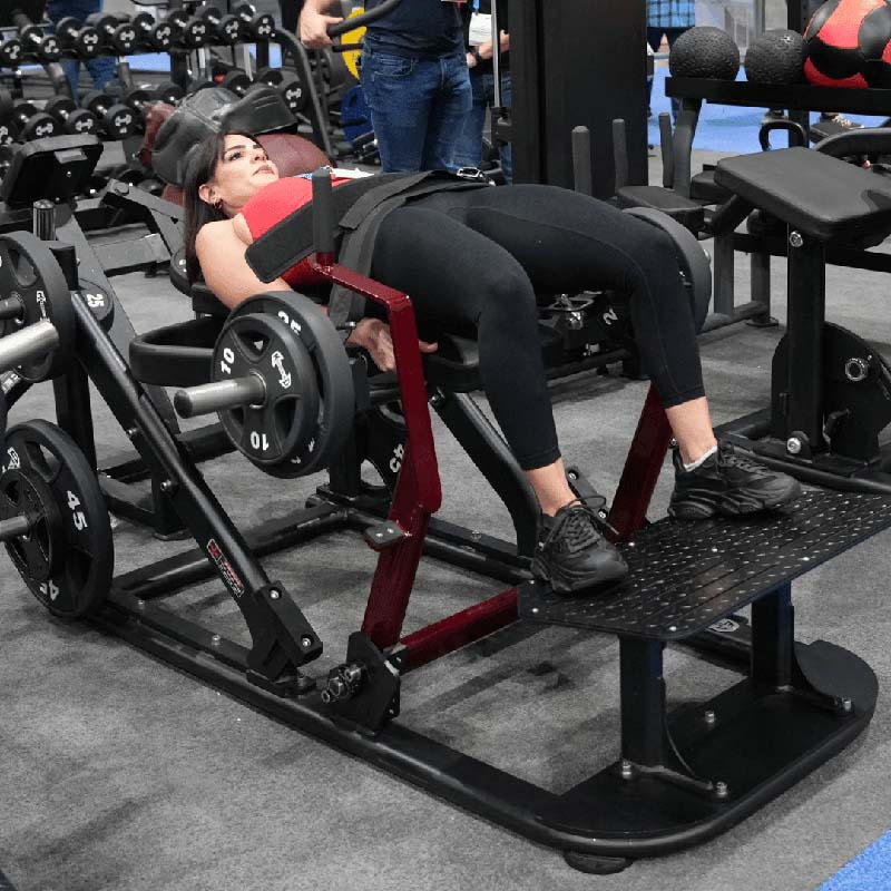 Woman performing hip thrust on a gym machine with weights.