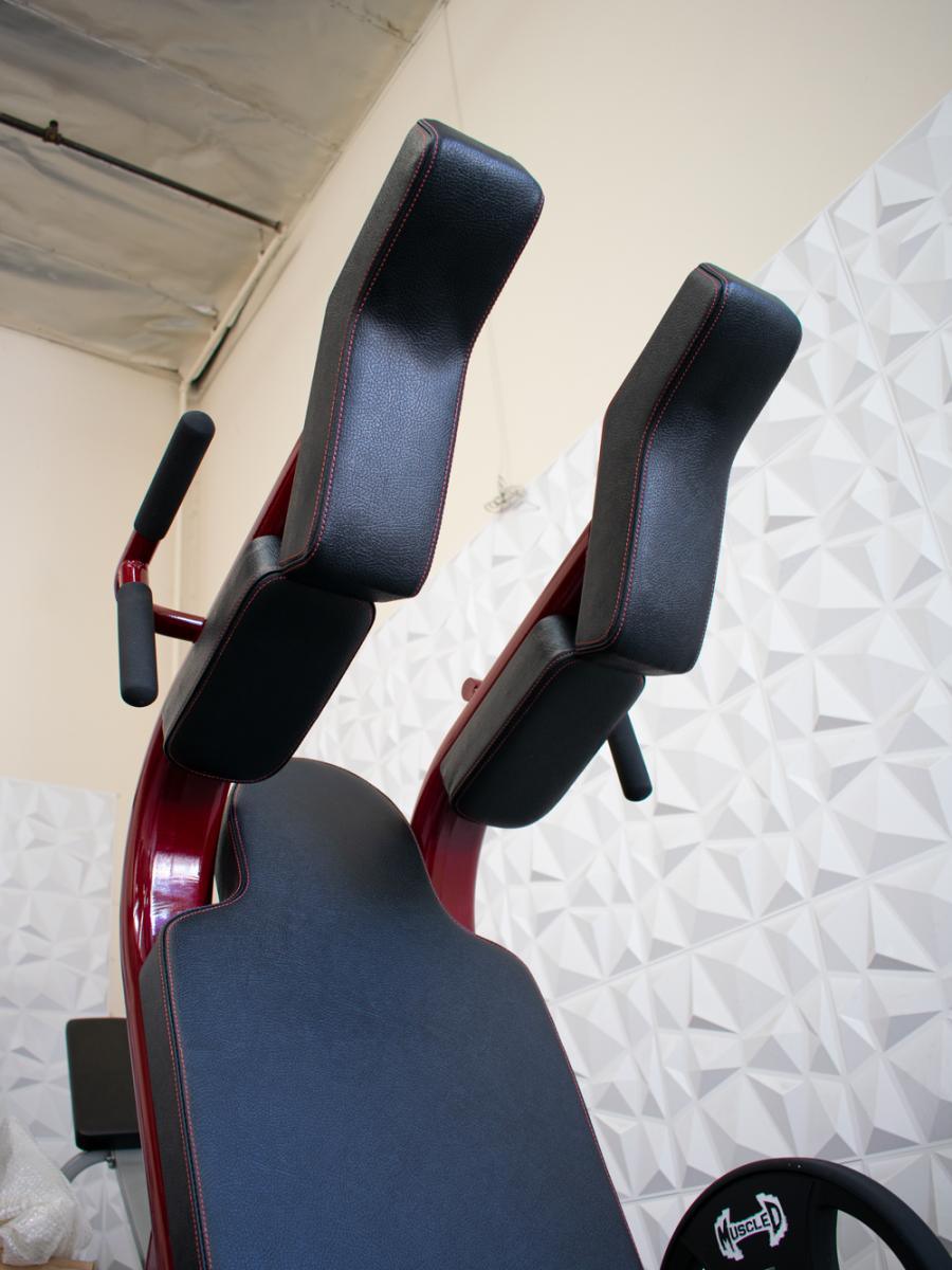 Close-up of a black padded leg extension machine with a red frame.
