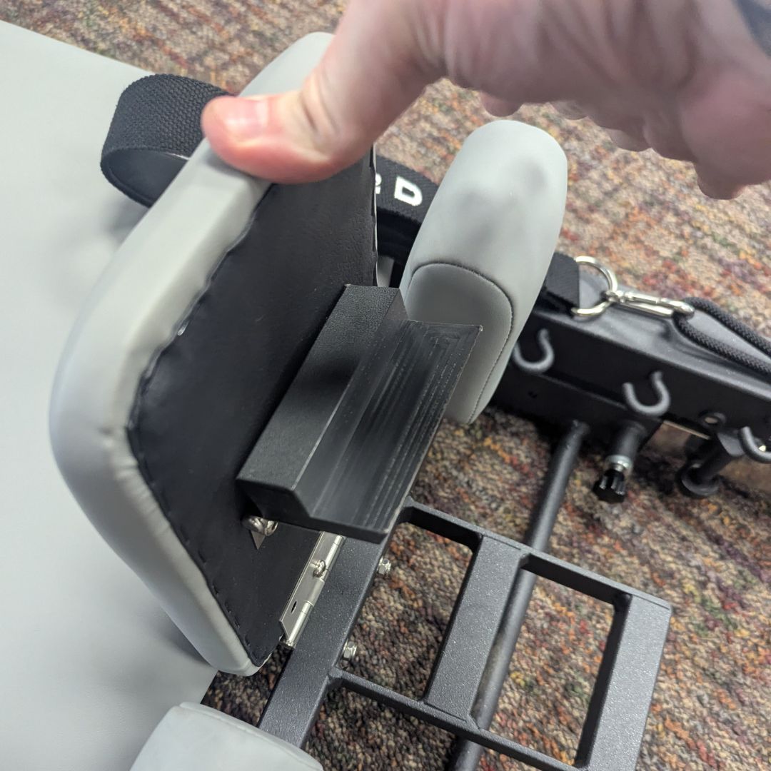 Close-up of a padded Pilates reformer with adjustable foot support.