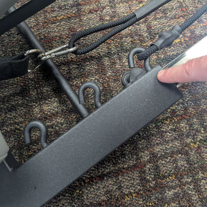 Close-up of a Pilates table frame with metal hooks and black straps.