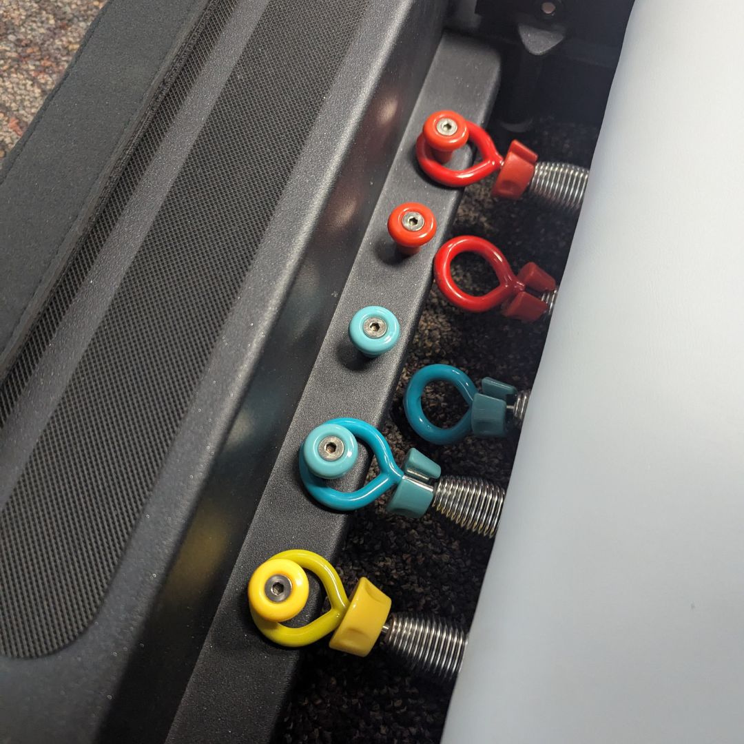 Close-up of colorful pins and springs on a Pilates reformer table.