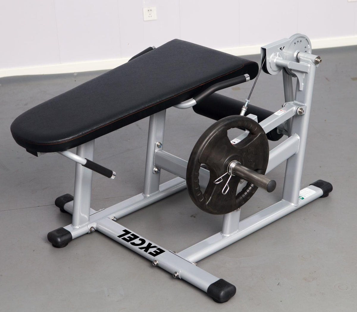 Leg extension bench with barbell and weight plate in a gym.