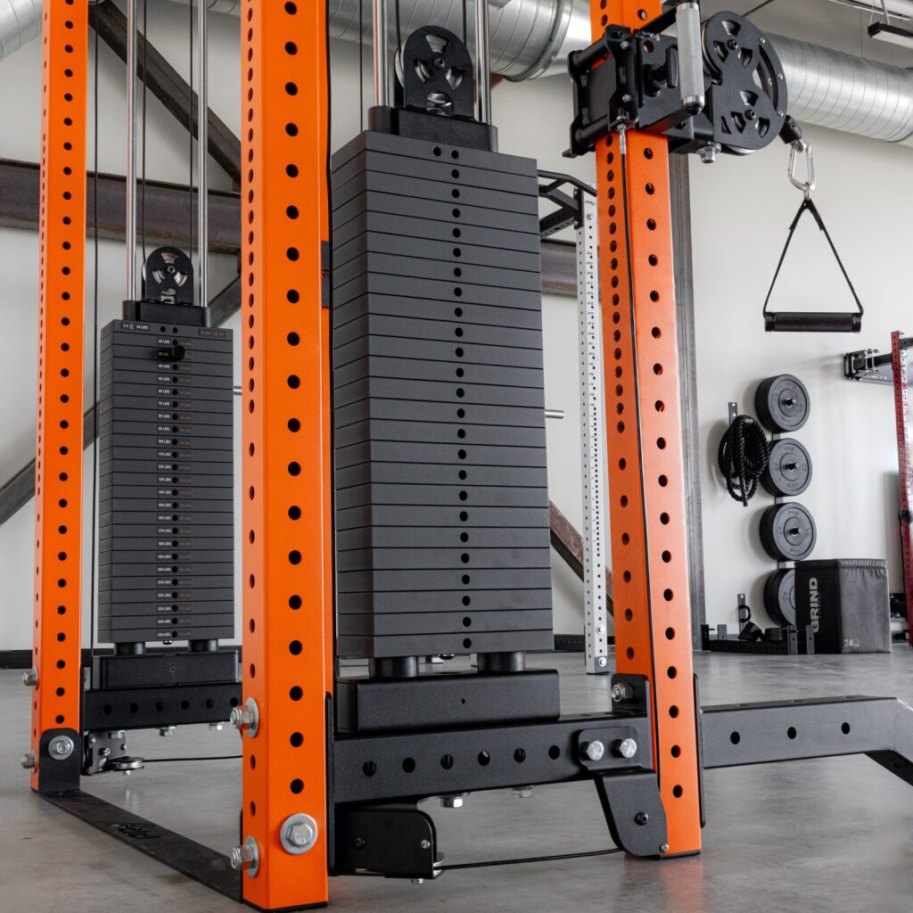 Industrial gym with orange squat rack and stacked weight plates.