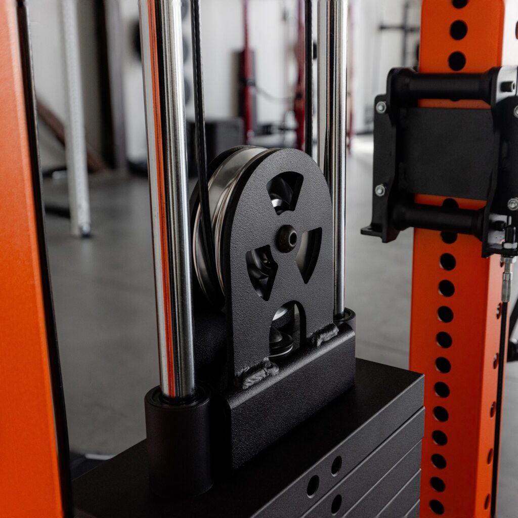 Close-up of weight plate and pulley on cable machine in gym.