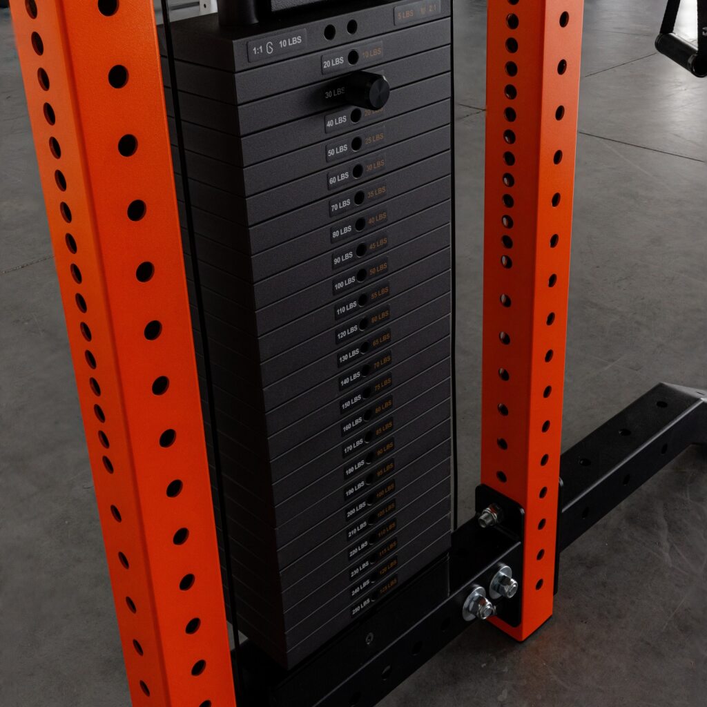 Stack of weight plates on a black weight stack inside an orange gym rack.