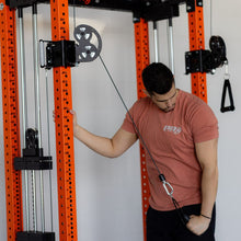 Man in pink t-shirt using a cable machine in a gym.