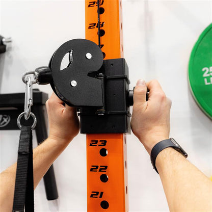 Person adjusting a clamp on an orange gym rack post.
