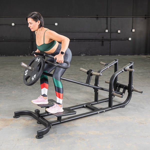 Woman using a T-Bar Row machine with a 45 lb weight plate in a gym.