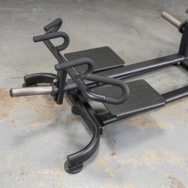 Black calf raise machine with diamond plate foot platforms on concrete floor.