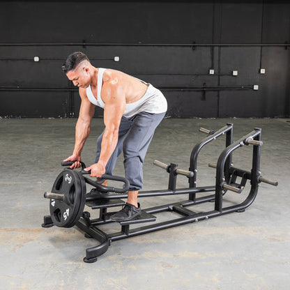 Man using a T-Bar Row Machine for back workout in a gym setting.