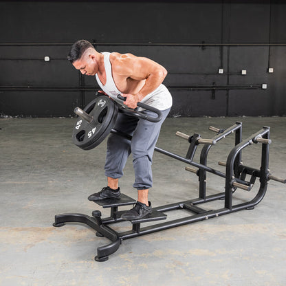 Man using T-Bar Row Machine with 45 lb weight plate for back exercises in gym.