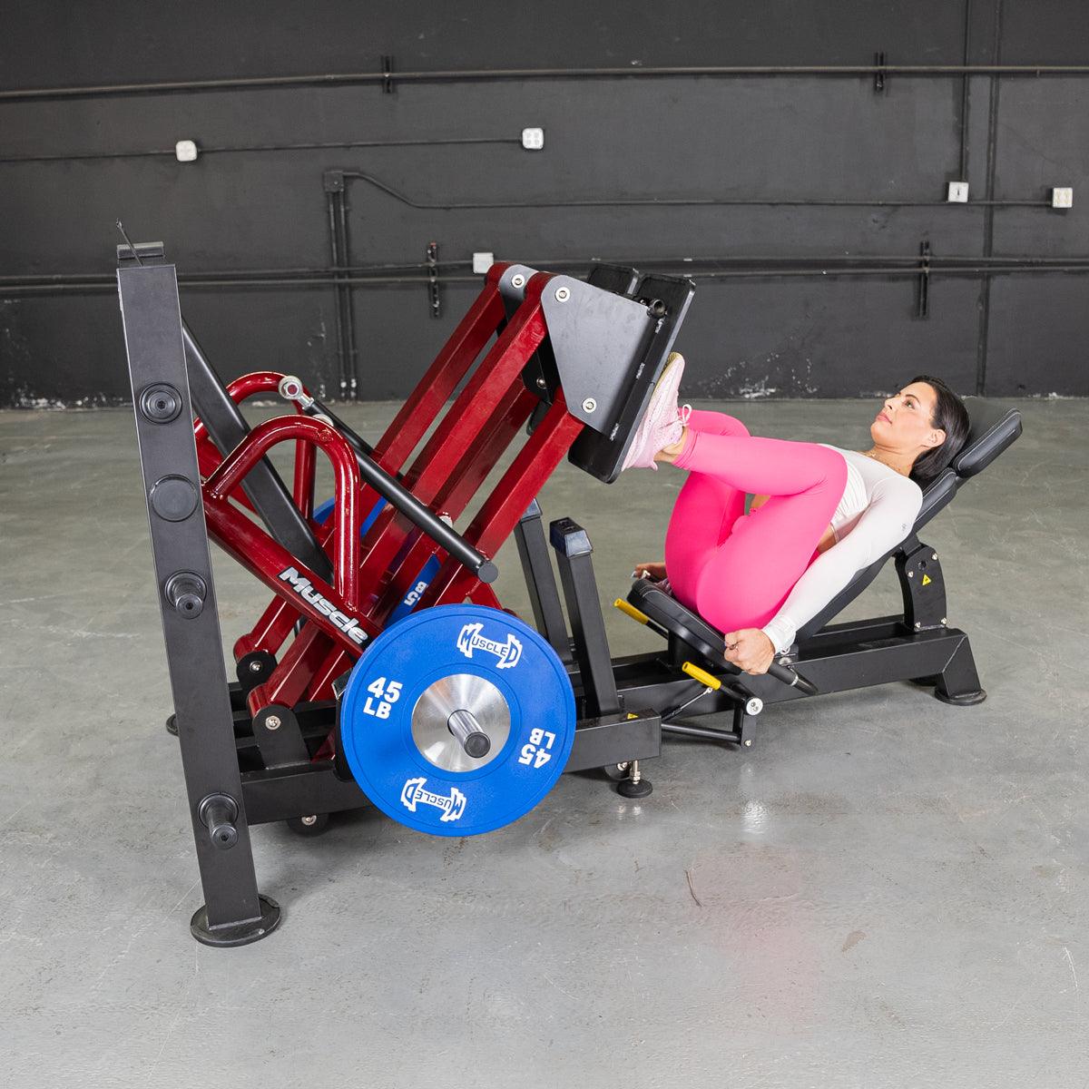 Woman performing a 45-degree iso-lateral leg press with blue weight plates.