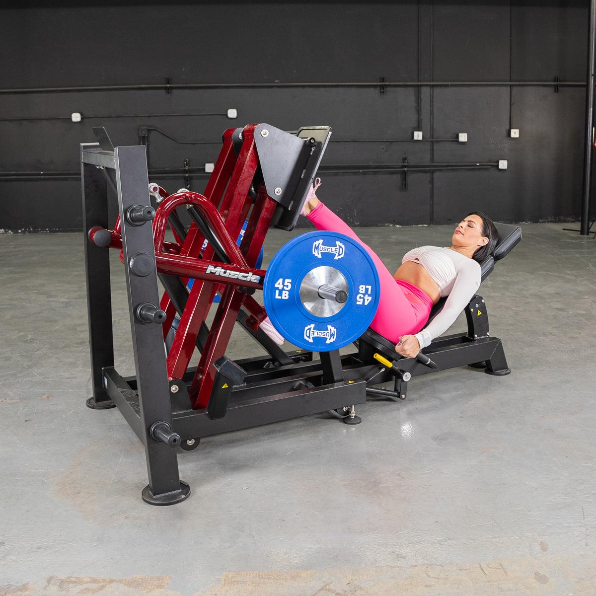 Woman using 45-degree iso-lateral leg press machine in gym.