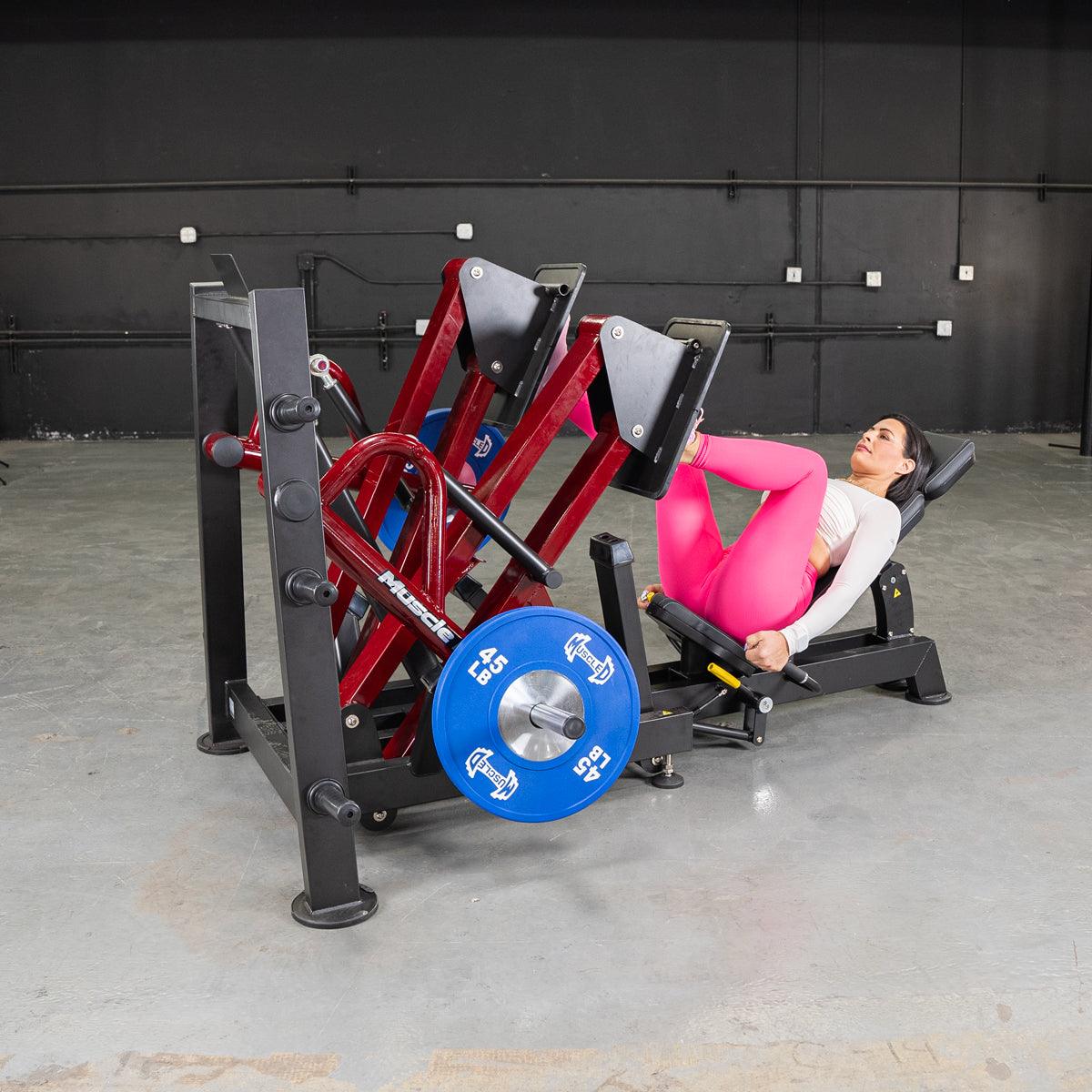 Woman using a 45-degree iso-lateral leg press machine with blue weight plates.