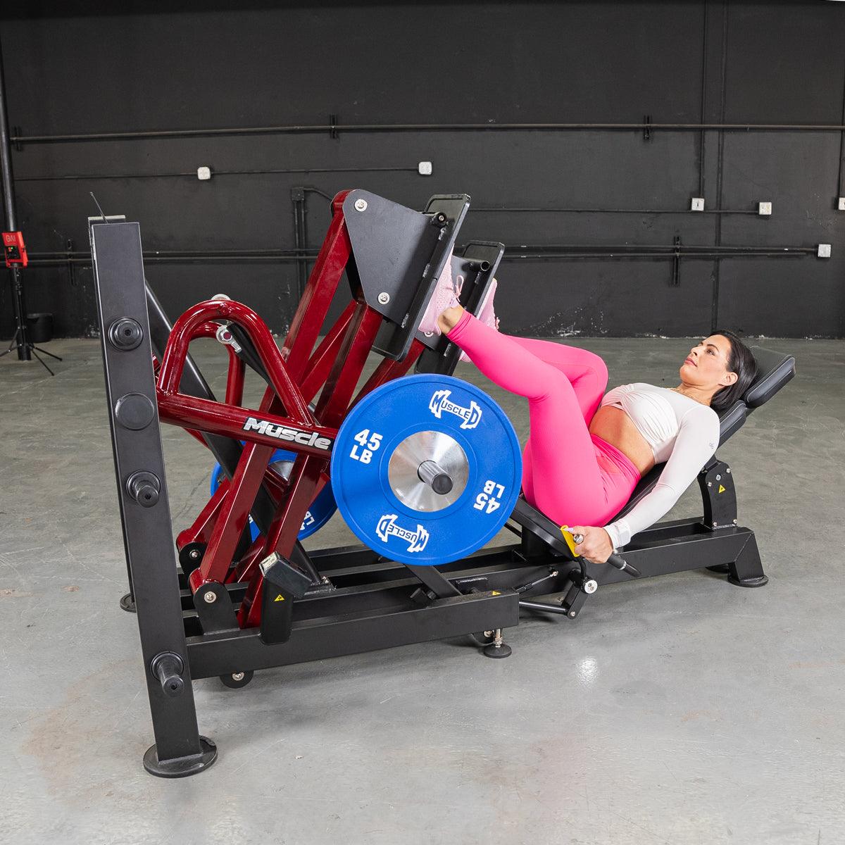 Woman uses a 45° iso-lateral leg press with blue 45 lb plates.