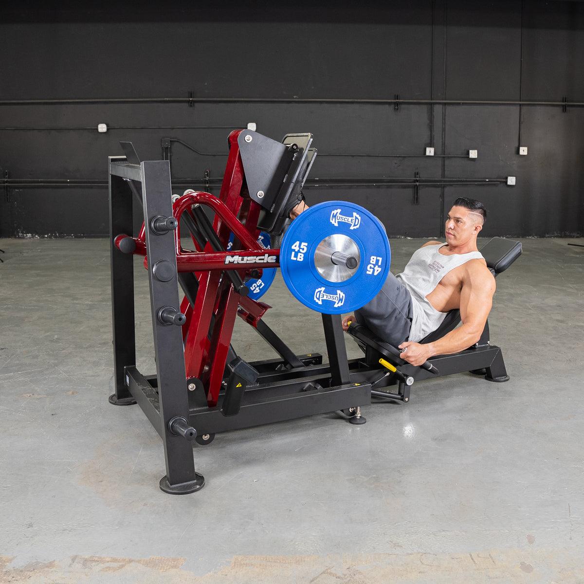 Man training on a 45-degree iso-lateral leg press with blue 45 lb plates.