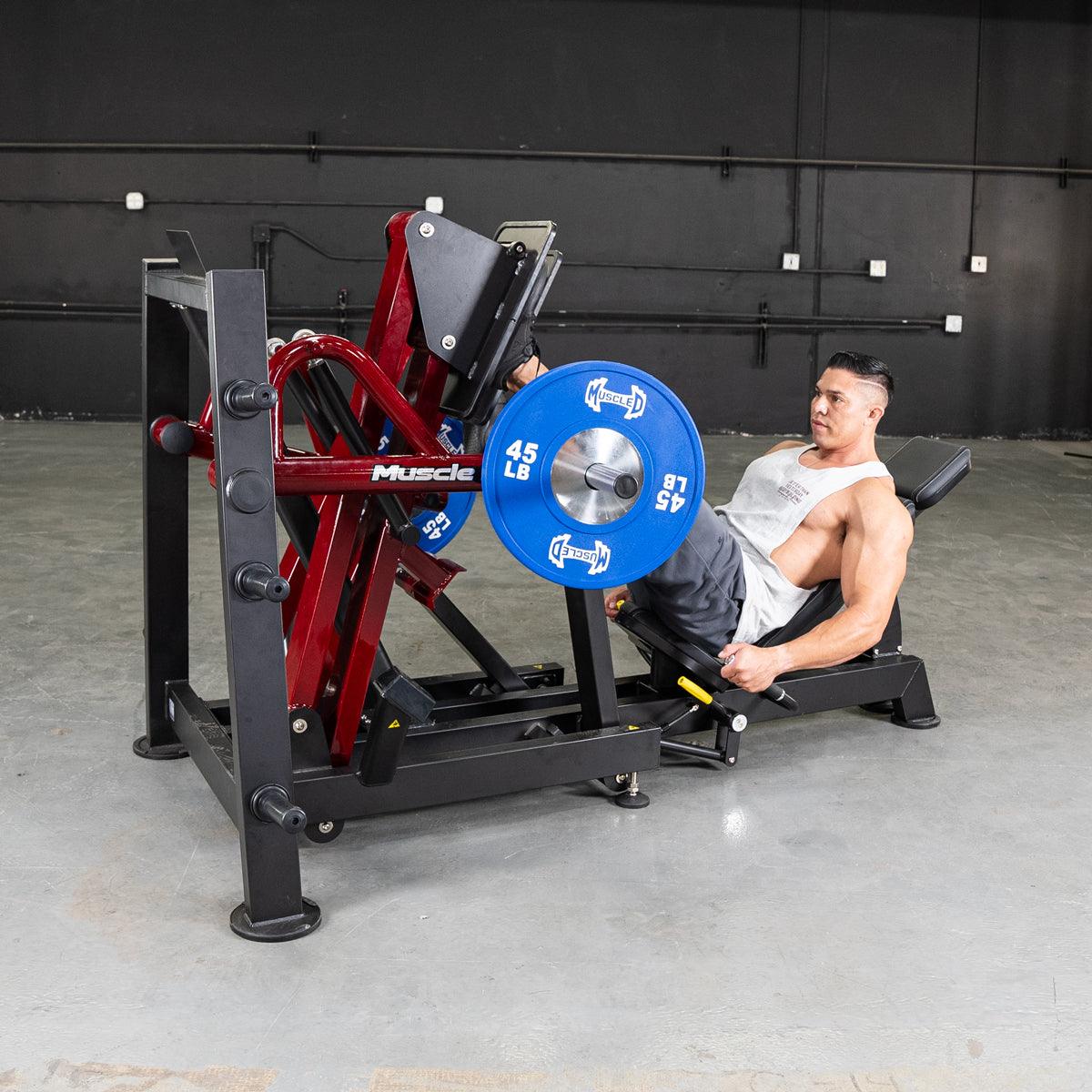 Man using a 45-degree leg press machine with blue 45 lb plates.