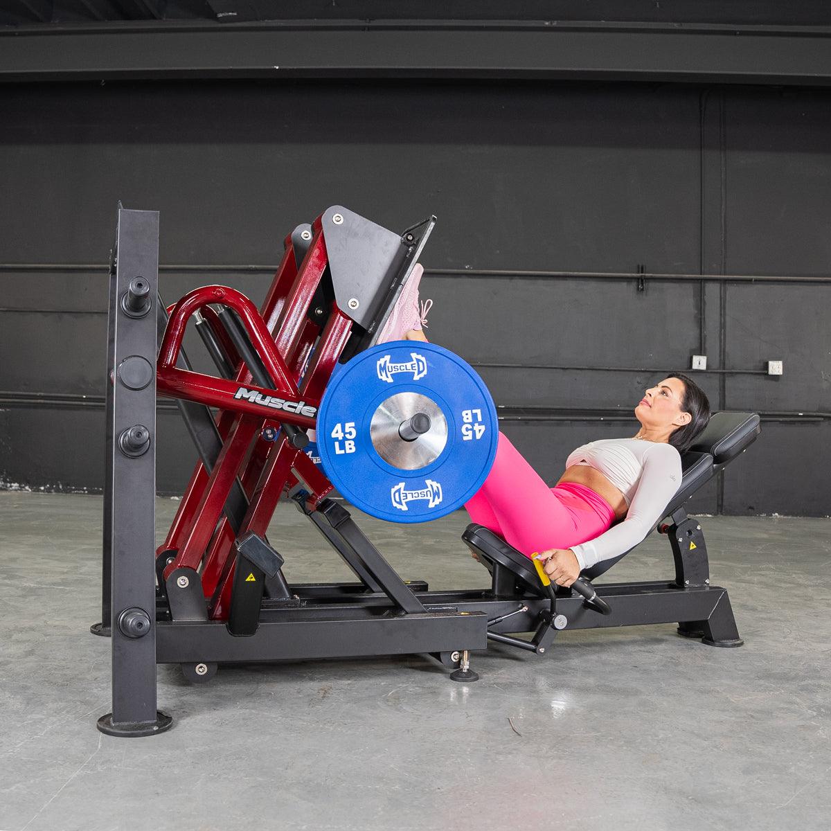 Woman using a leg press machine with 45-lb blue plates in a gym