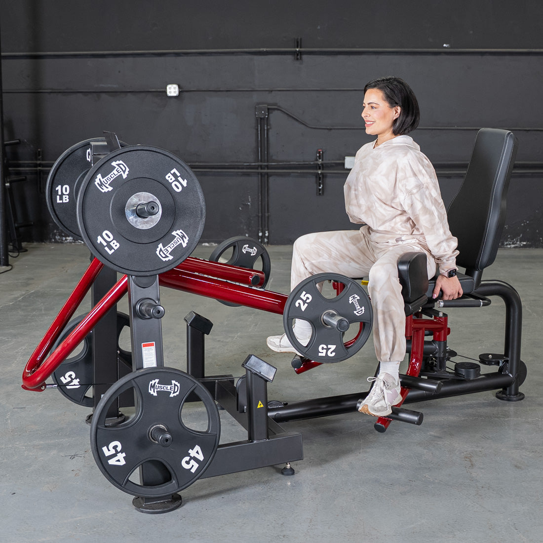 Woman seated on a Power Leverage Abductor/Adductor gym machine with weights.