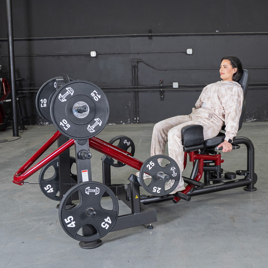 Woman seated on Power Leverage V2 Abductor Adductor machine in gym.