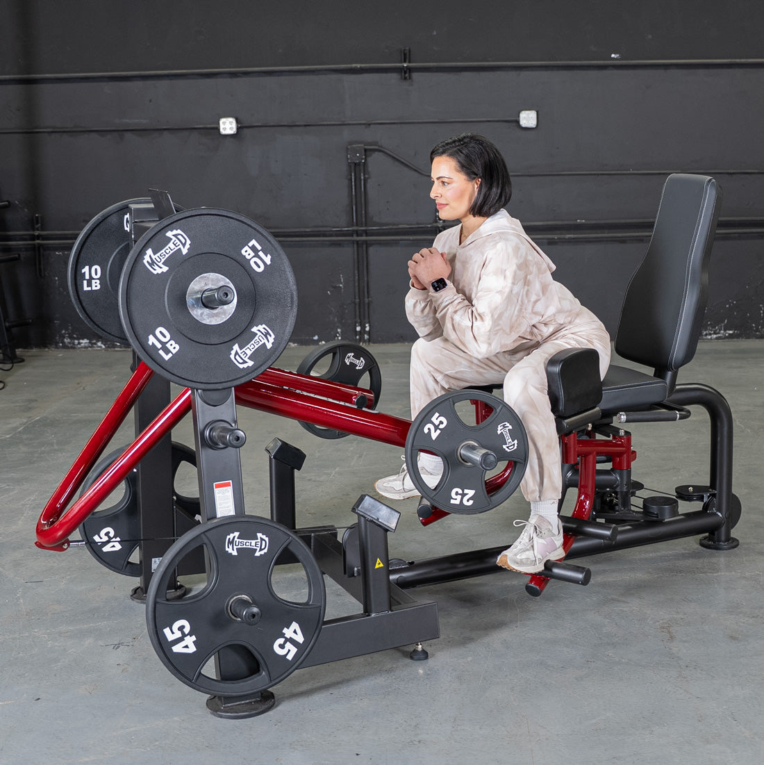 Woman seated on a Power Leverage V2 abductor/adductor machine with weights.