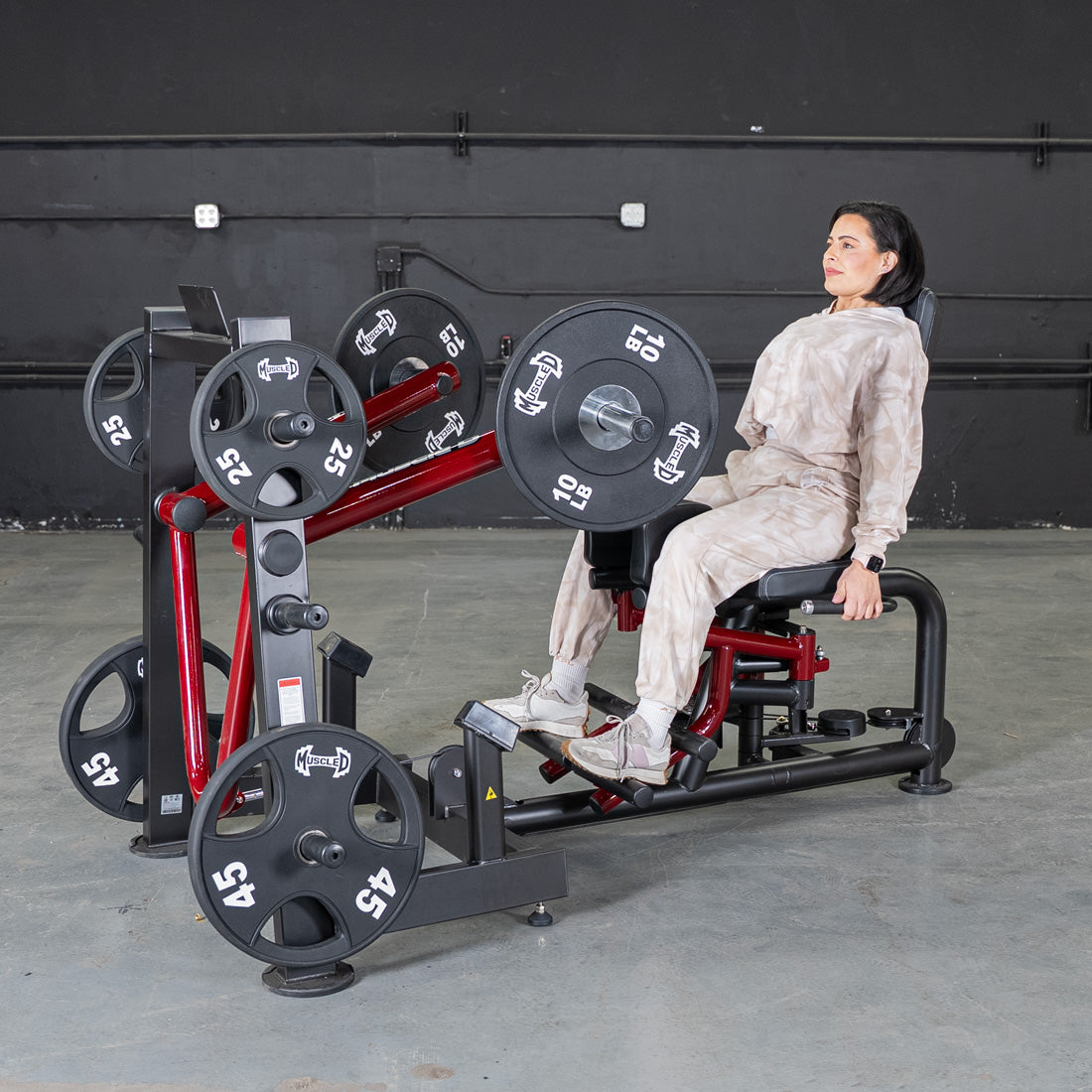 Woman seated on leg abductor/adductor gym machine with weights.