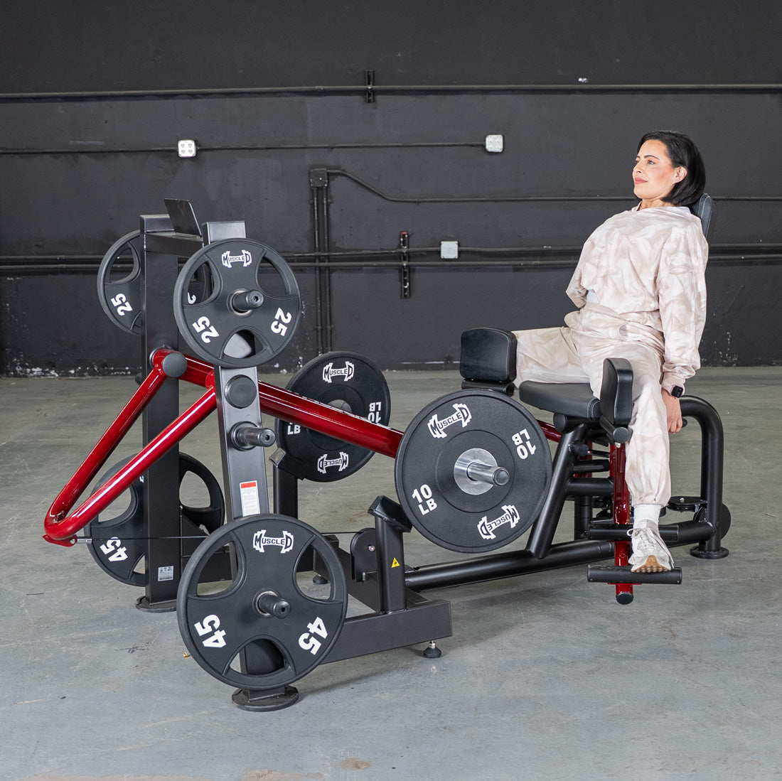 Woman using a power-leverage abductor/adductor gym machine.
