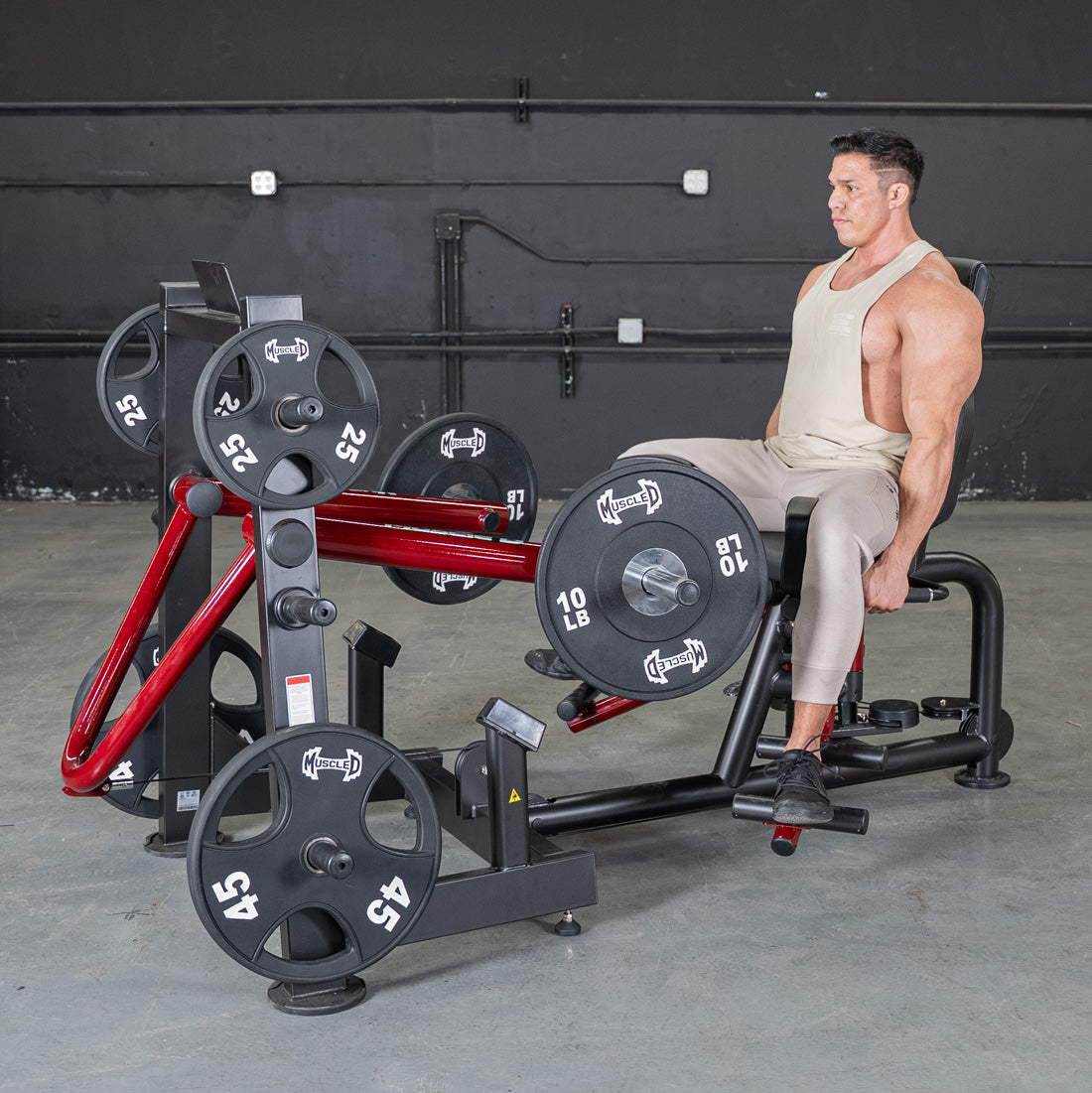 Muscular man seated on a Power-Leverage Abductor/Adductor machine with weights.