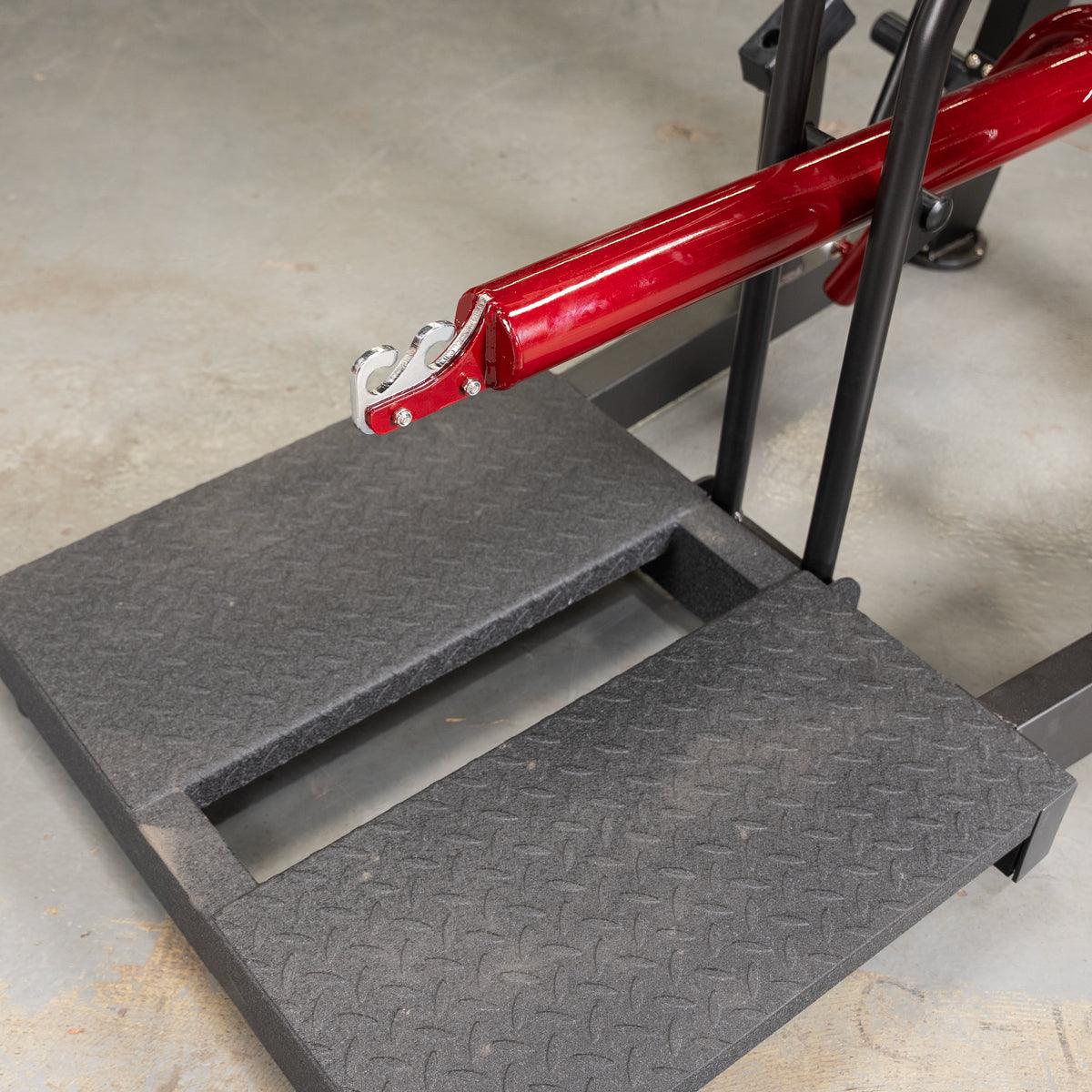 Red power-leverage bar attached to a belt-squat platform.
