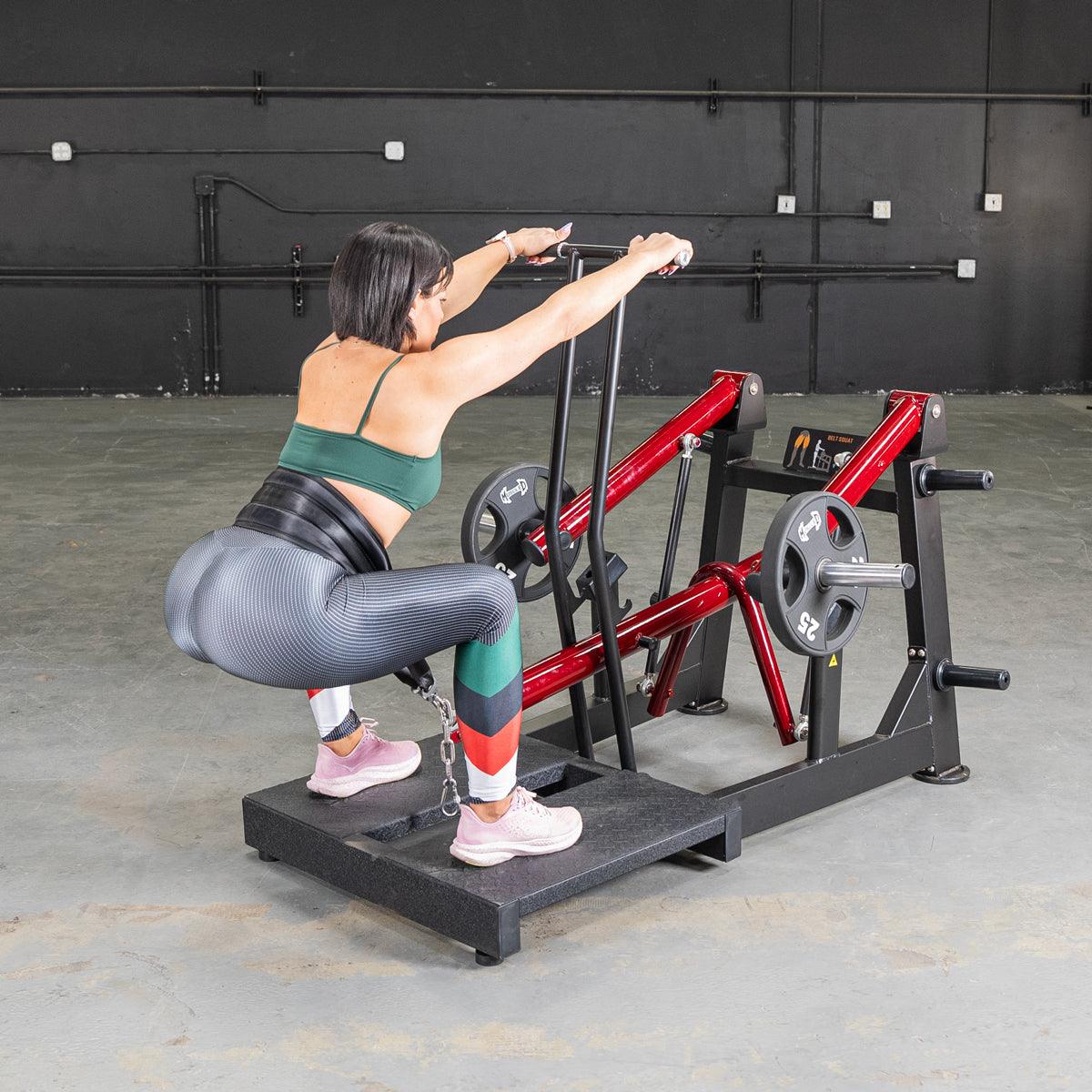 Woman using Power Leverage V2 belt squat machine with weights.