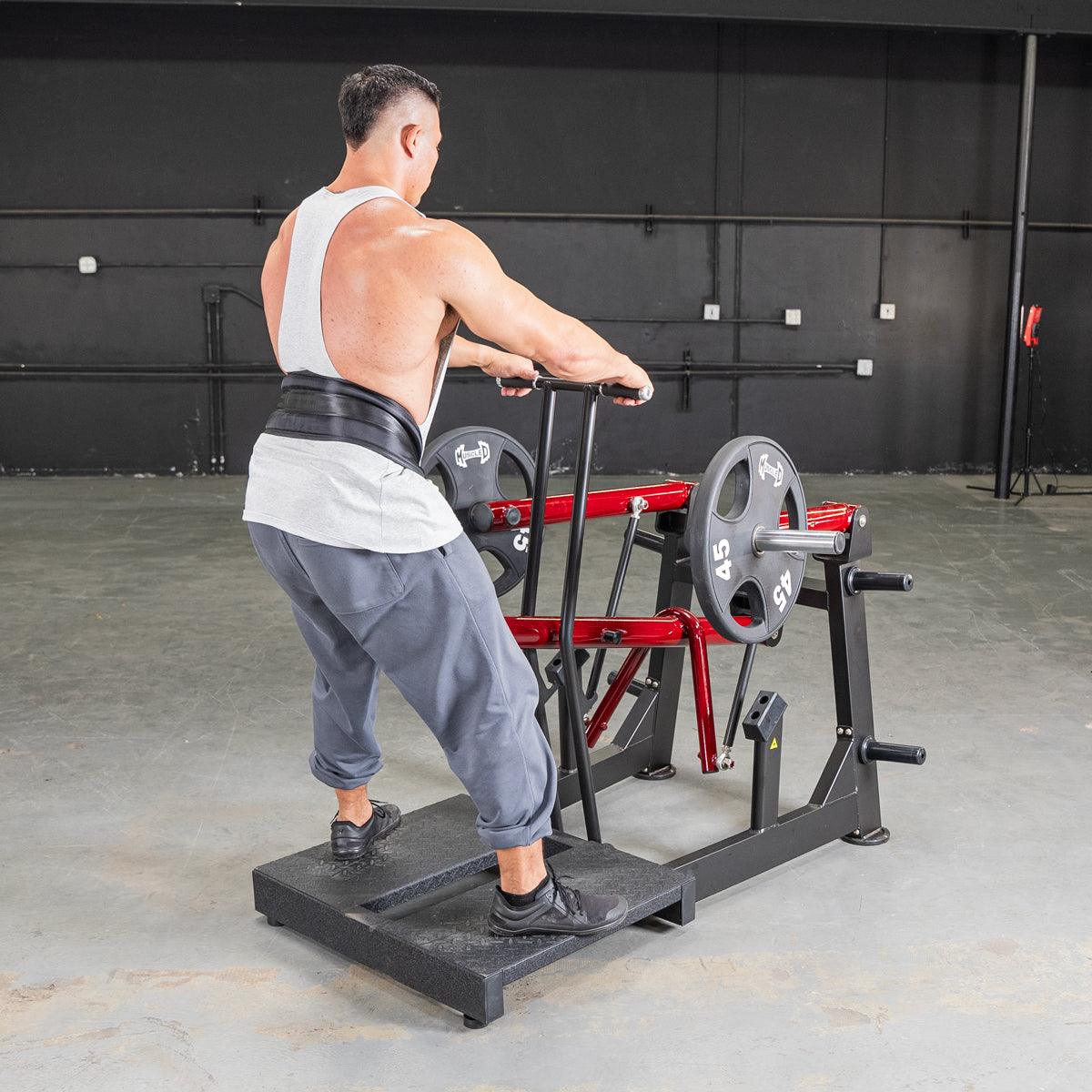 Man performing belt squat on a leverage machine in a gym.