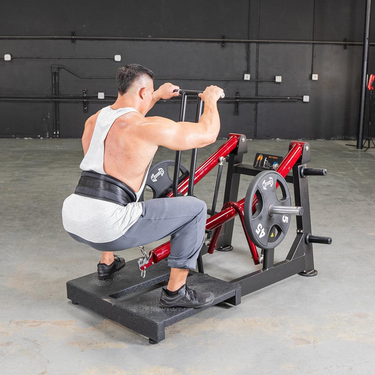 Man performing belt squat on a red Power Leverage machine with plates.