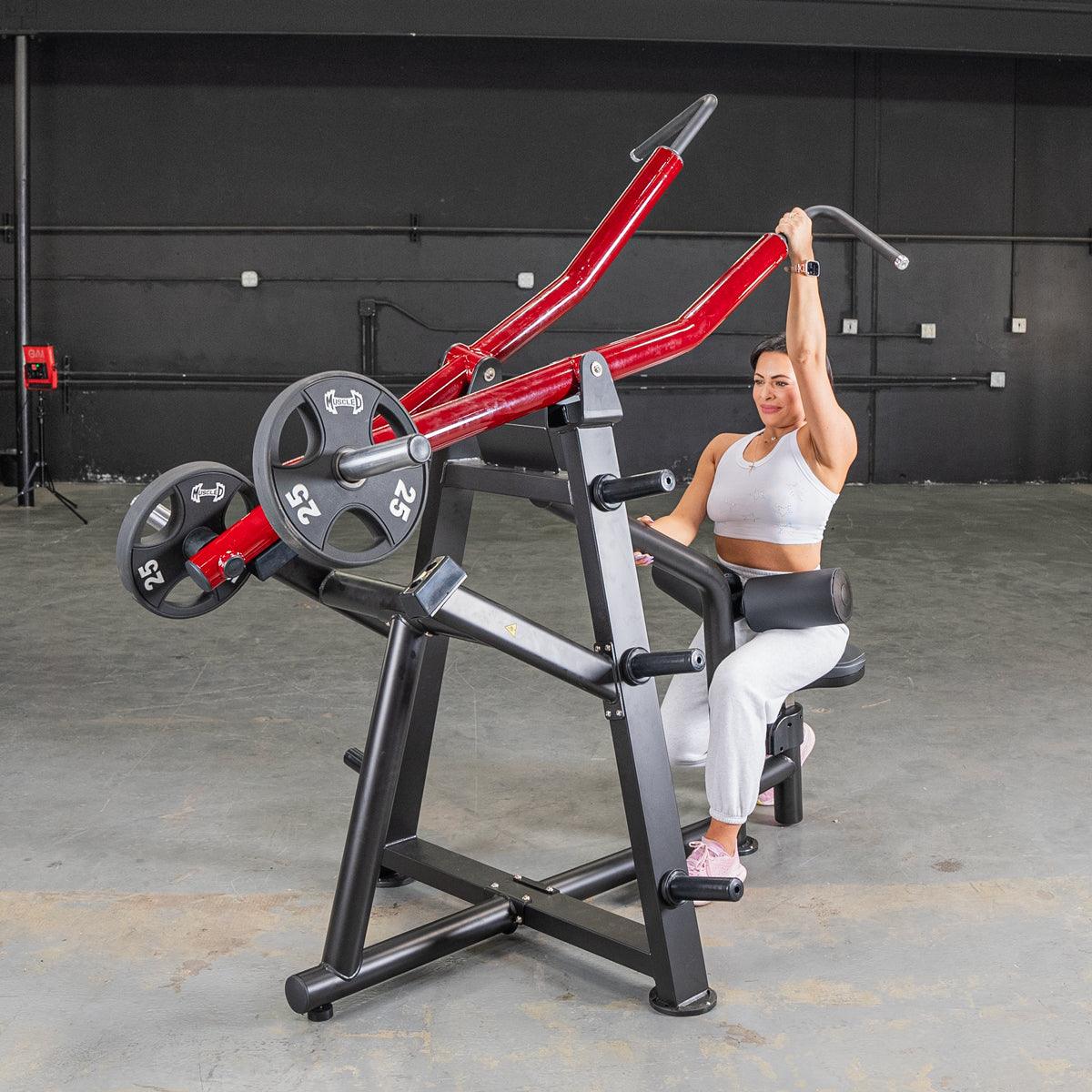 Woman using a red plate-loaded lat pulldown machine in a gym.