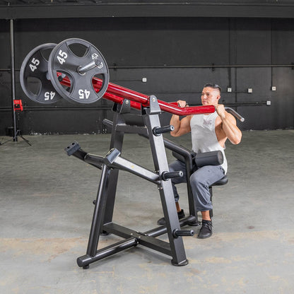 Man using red shoulder press machine with 45 lb weights in gym.