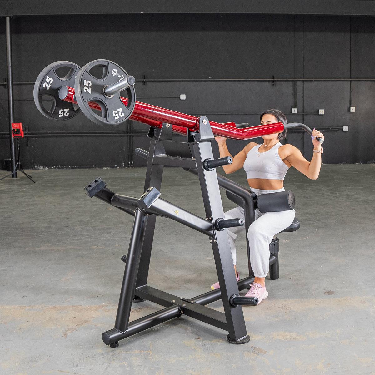 Woman using seated row machine with red grips in gym.