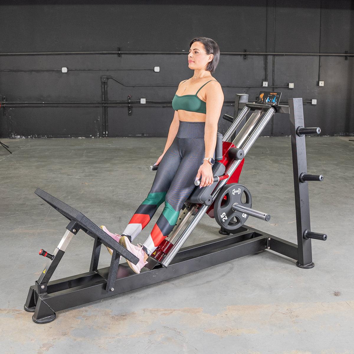 Woman on a Power Leverage hack squat calf raise machine in gym.