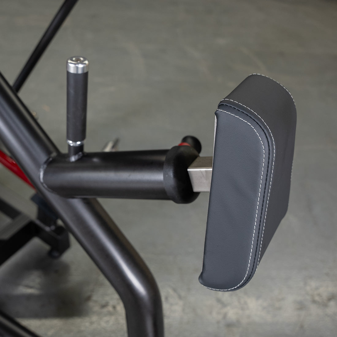 Black padded armrest on a fitness machine with ergonomic handle.