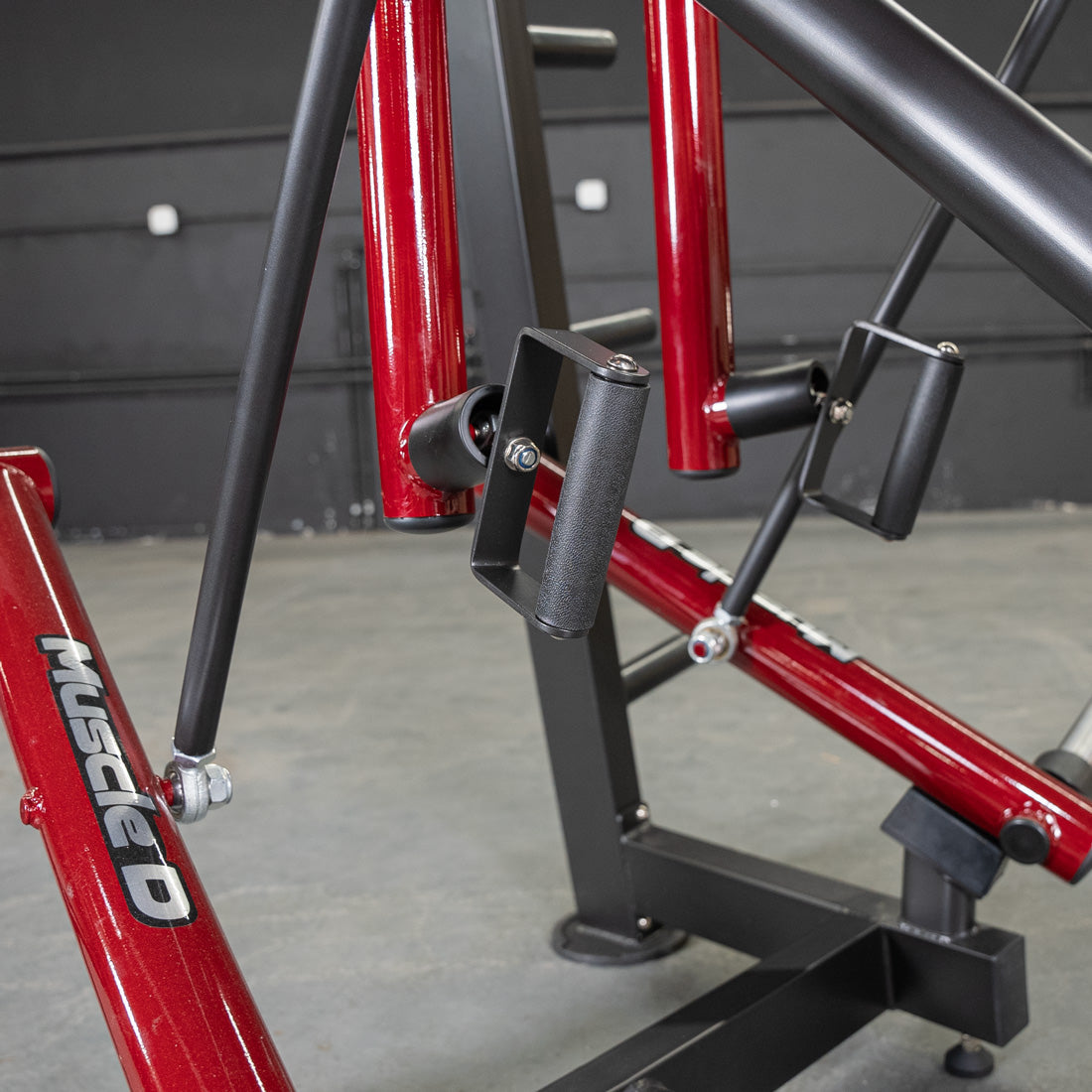 Muscle D Fitness equipment with red and black frame, featuring ergonomic handles.