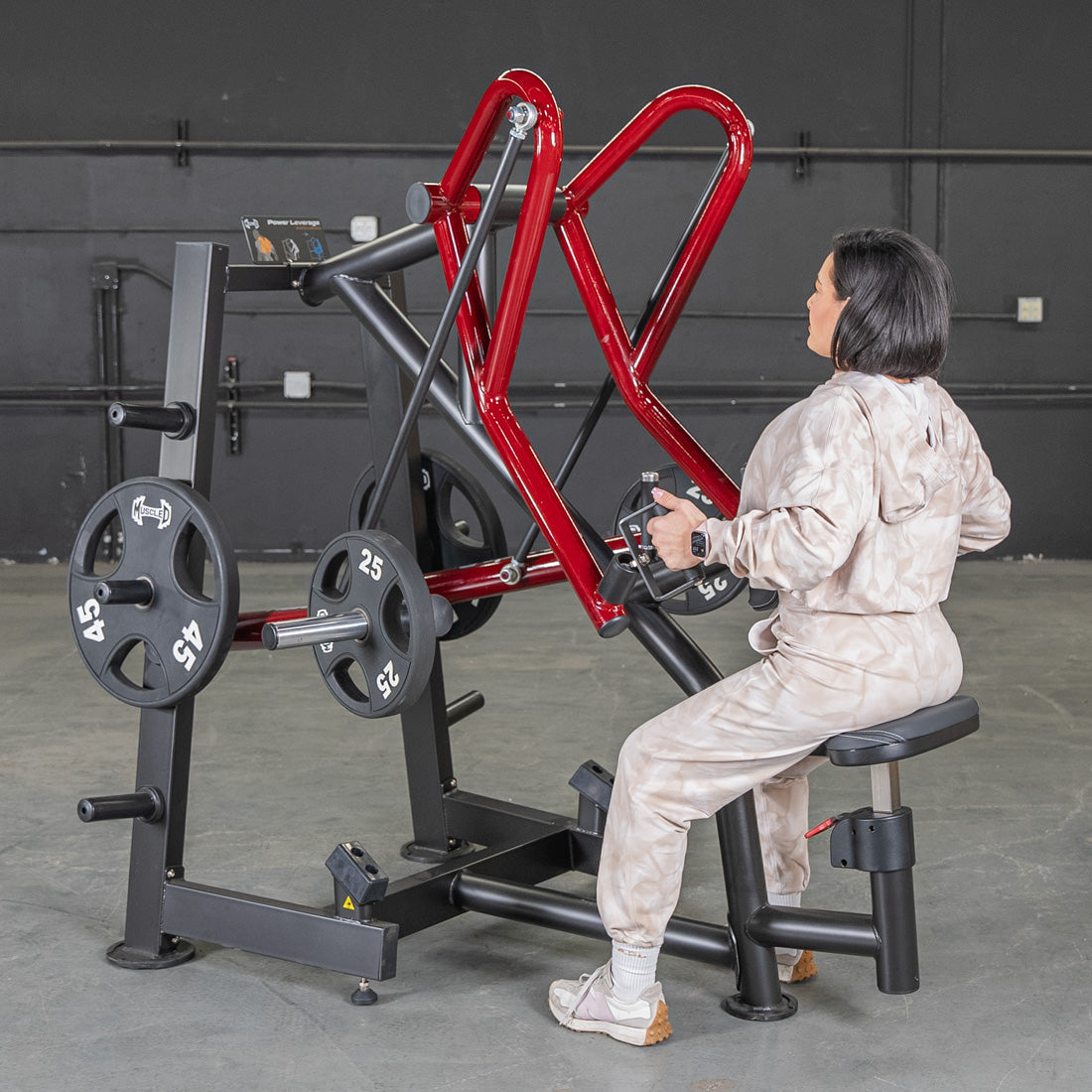 Woman using a red plate-loaded seated row machine in a gym.