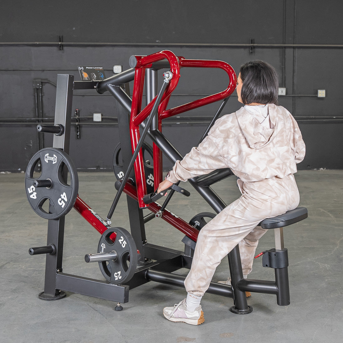 Woman using a red plate-loaded row machine in a gym.