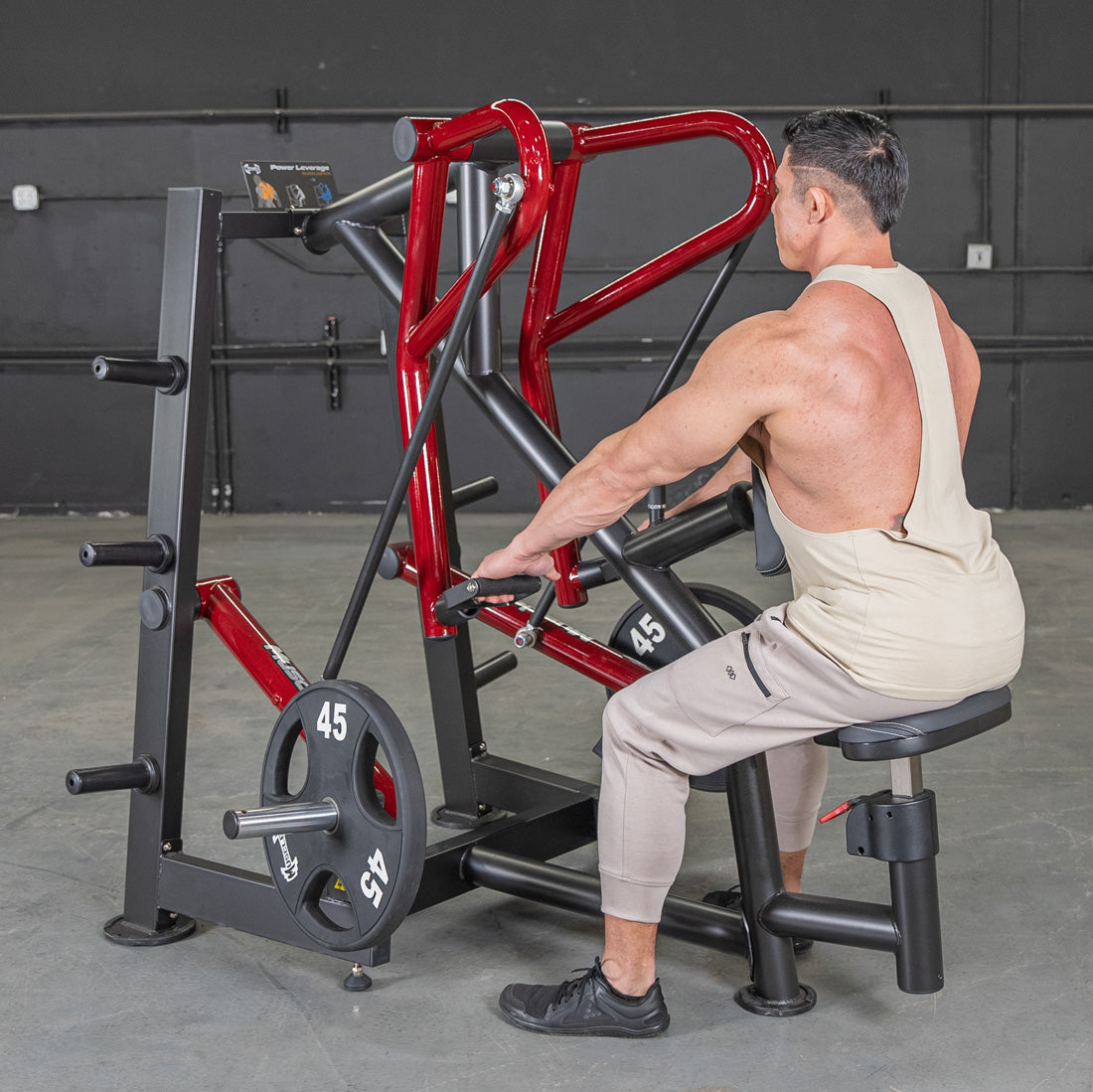 Man using Body-Solid leverage row machine with red frame in gym.