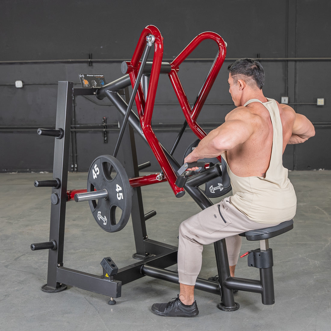 Man using Body-Solid leverage row machine with red handles in gym.