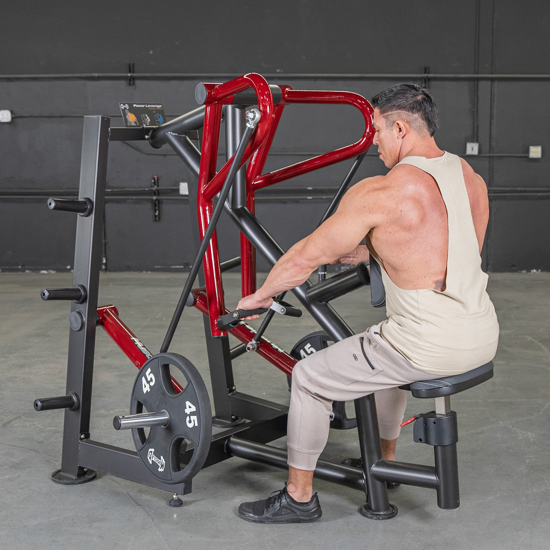 Man using red and black seated row machine for back workout in gym.